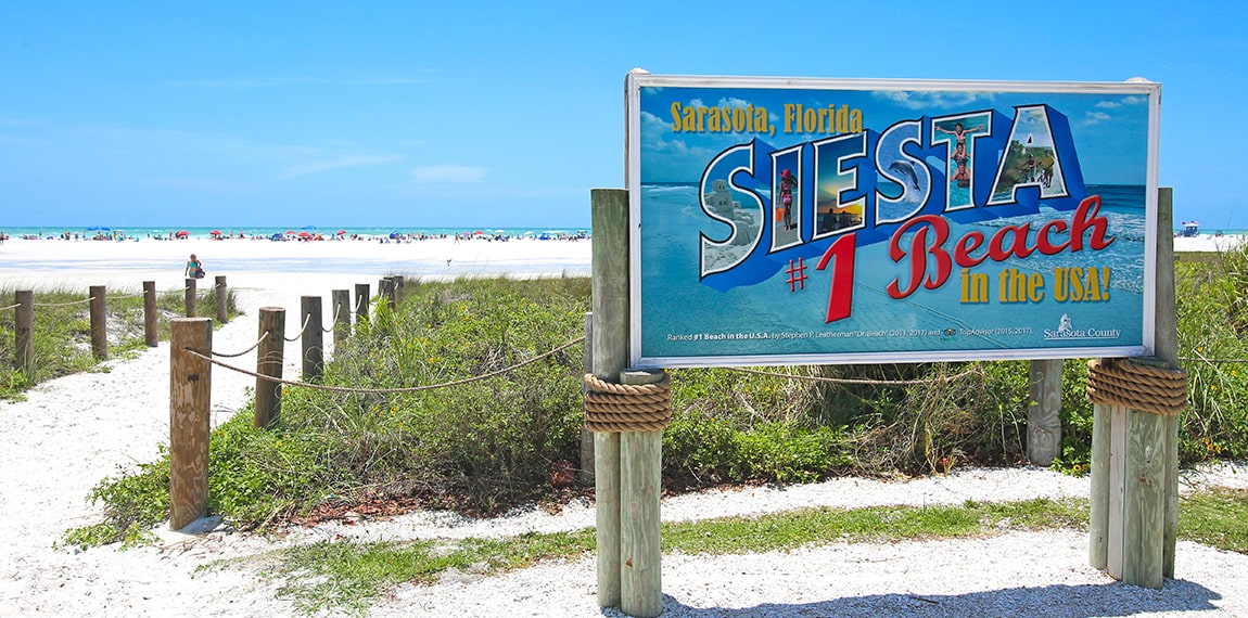 siesta beach sign next to entrance to beach