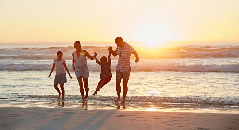 family playing on beach at sunset