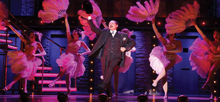 Man dancing on stage in front of show girls