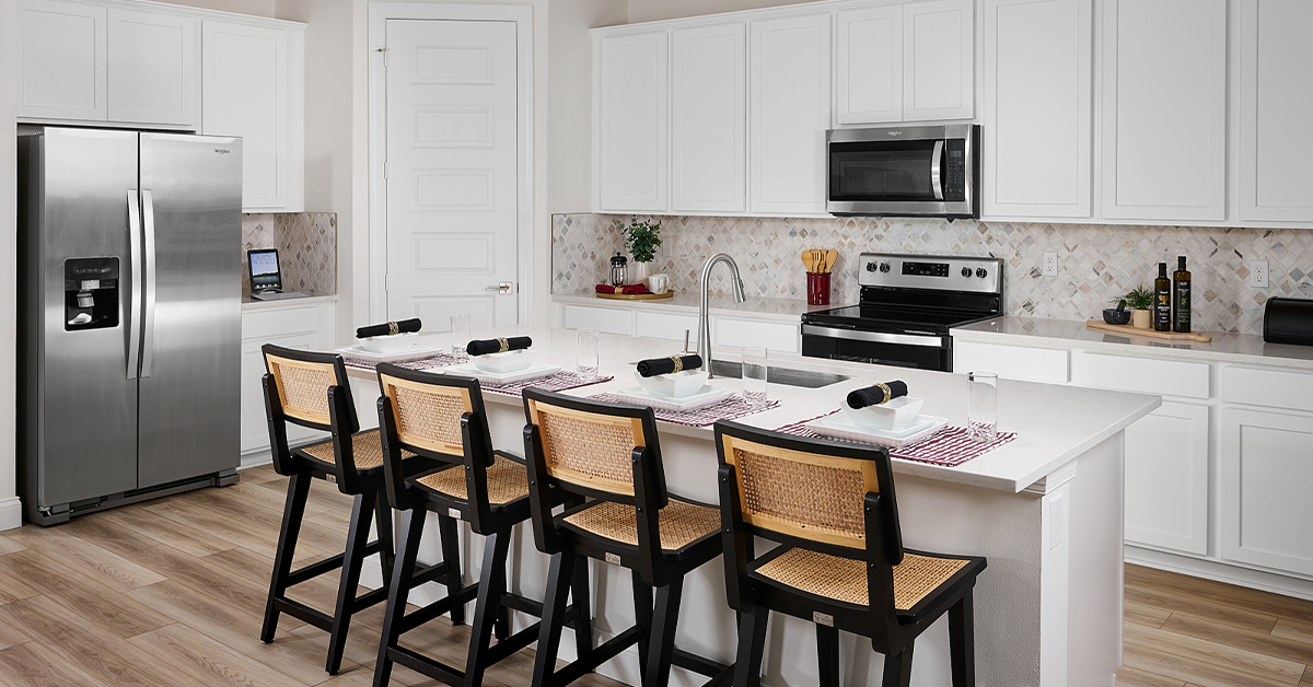 Kitchen with white cabinets, island seating, and stainless steel appliances.